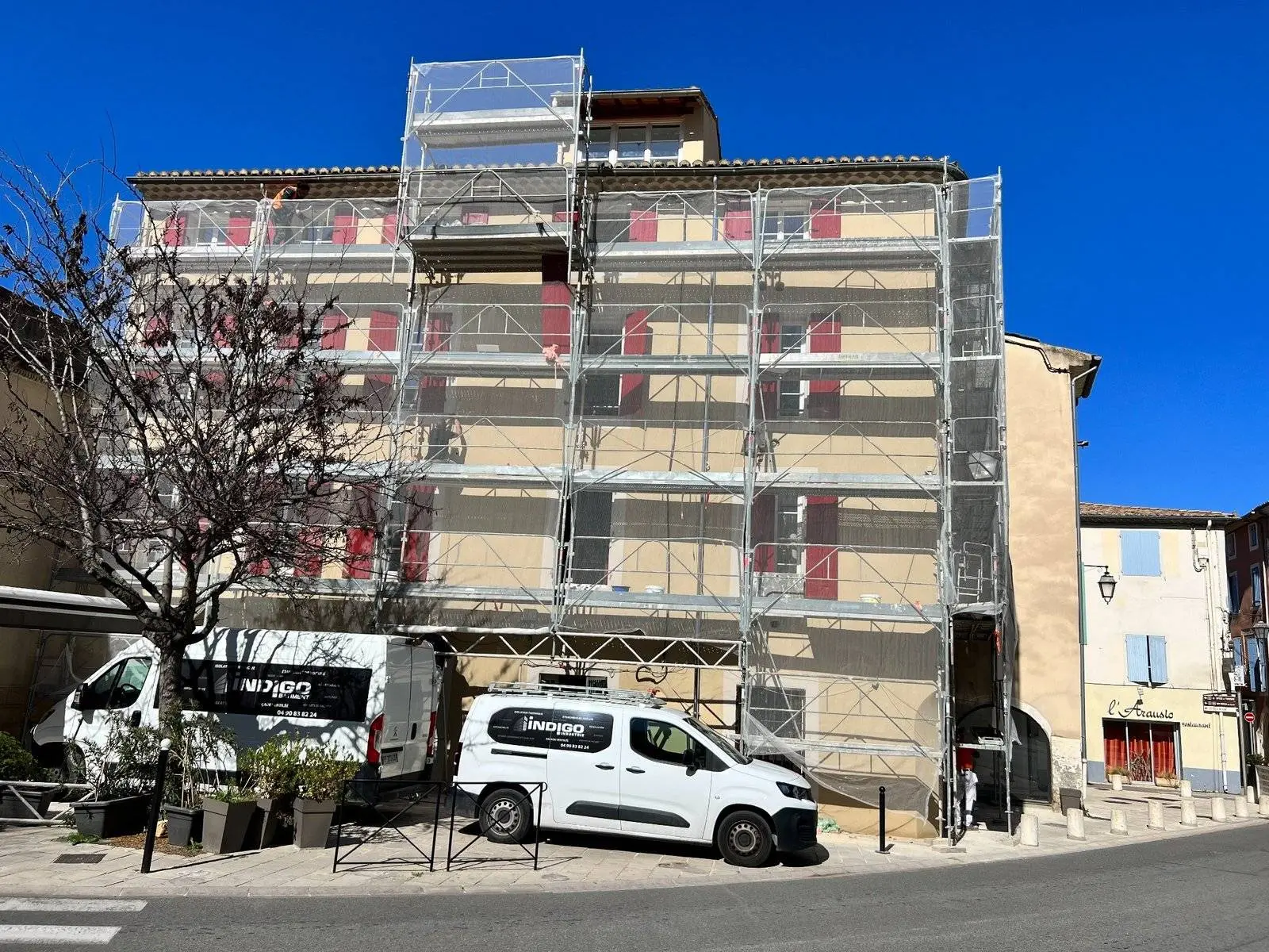 Chantier de ravalement sous échafaudage : application d'un enduit hydraulique projeté sur un immeuble