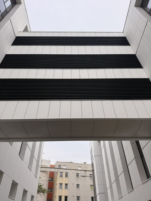 Vue en contre-plongée de la passerelle et des grilles de ventilation du bardage