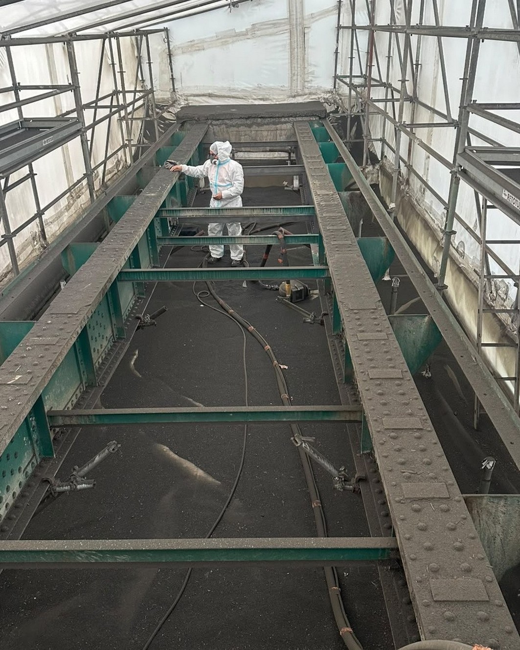 Opérateur Indigo Industrie en cagoule à adduction d'air pendant le sablage sous confinement